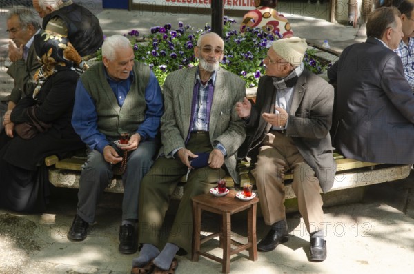 Bursa, Turkey. April 21st 2014 Old Turkish men chatting and drinking tea in a tree shaded square, Bursa City, Turkey