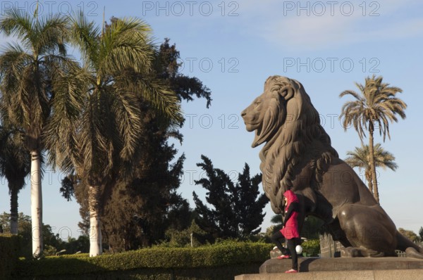 Cairo, Egypt. December 10th 2009 Young Egyptian Muslim women poses for photographs beside a statue of a lion, downtown Cairo, Egypt