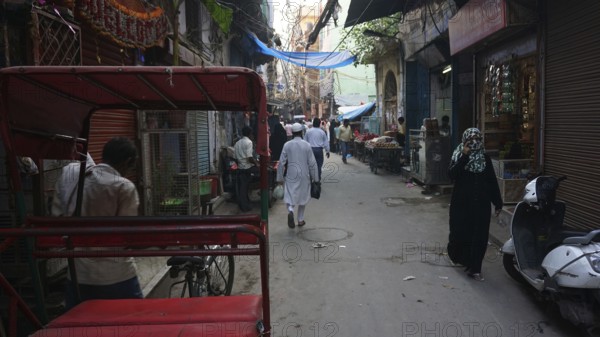 Quiet alley in a Muslim neighborhood of Delhi with isolated people and rickshaws, Delhi, India