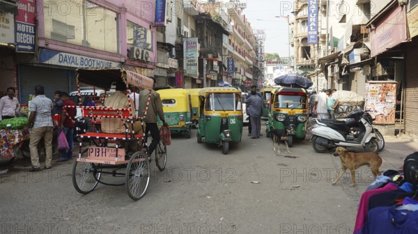 Busy shopping street with rickshaws and people in the bustling Indian city of Delhi, India