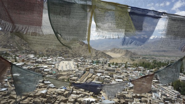 Colourful prayer flags waving in the wind, view of Leh Palace and mountains in the background, Ladakh, North India, Himalayas, India