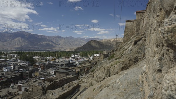 View of Leh on the mountainside with a stone wall and clouds in the sky, view from Leh Palace to Leh, Ladakh, North India, Himalayas, India