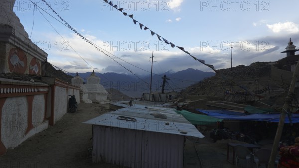 Monastery structures under a blue sky decorated with prayer flags, outskirts of Leh, Ladakh, northern India, Himalayas, India