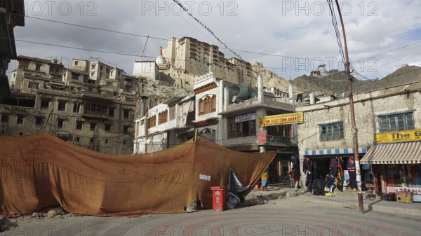 Leh Palace and historic buildings with market stalls and tents against a mountainous backdrop in Leh, Ladakh, North India, Himalayas, India
