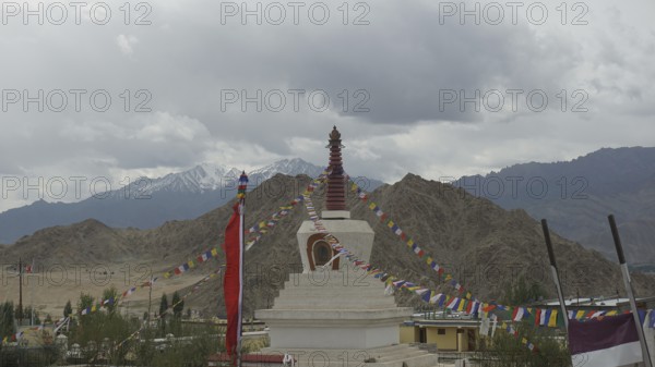 A stupa in Leh, surrounded by colorful prayer flags and mountain panorama in the background, Leh, Ladakh, North India, Himalayas, India