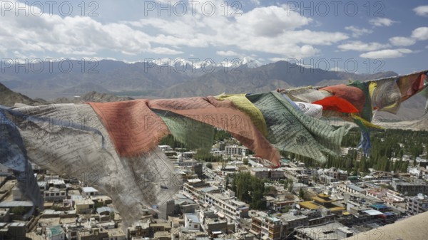Prayer flags fly over Leh, a city with mountains and cloudy sky in the background, view from Leh Palace, Ladakh, northern India, Himalayas, India