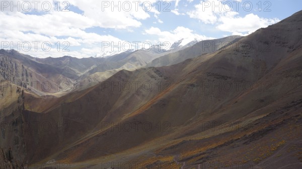 Wide valley surrounded by majestic mountains under bright skies, trekking at Stok La Pass in Ladakh, Himalayas, India