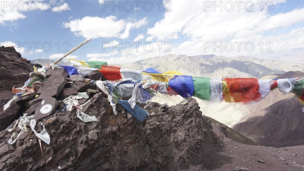 Colourful prayer flags flying over a rocky mountain landscape, trekking at Stok La Pass in Ladakh, Himalayas, India