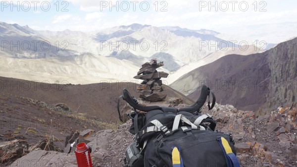 Break at the highest point of Stok La Pass, backpack in the foreground with rocky mountain scenery, stone tower, trekking on Stok La Pass in Ladakh, Himalayas, India