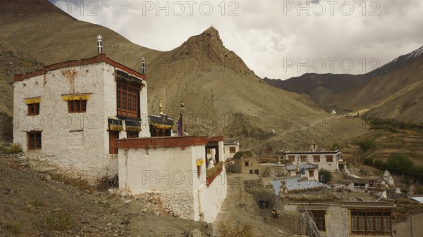 Traditional village on a mountainside under dramatic sky in the Himalayas, trekking in Ladakh, Himalayas, India