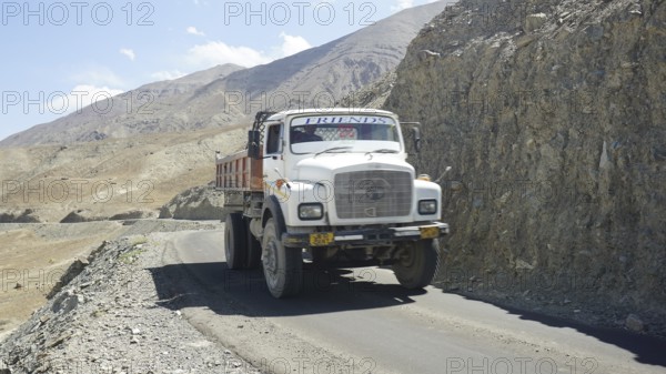 A sturdy truck on a narrow mountain road on a barren mountain landscape, Ladakh, Himalayas, India