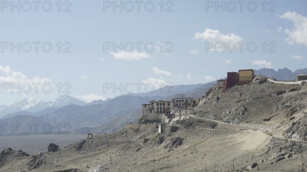 Building on a mountainous hill with a narrow road and blue cloud cover, Ladakh, Himalayas, India