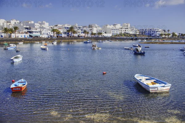 Coastal town with lagoon (Charco de San Ginés), scattered boats on calm water, white buildings on the horizon, Arrecife, Lanzarote, Canary Islands, Spain