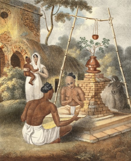 Brahmins at a Toolsee altar, India, authentic, digitally restored reproduction from a 19th century model, exact date of depiction unknown, historical, a family and a priest performing a ritual in front of a small temple