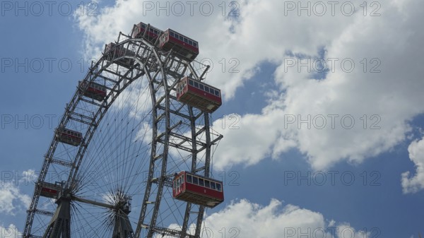 Large Ferris wheel with red cabins against a partly cloudy sky, Prater, Vienna