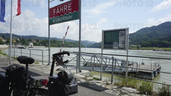 Cycling in front of a ferry with a view of the Danube and mountains, cycling on the Danube cycle path, Austria