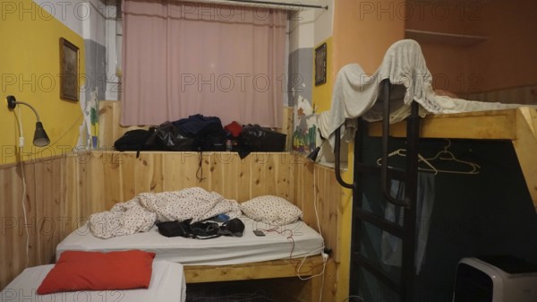 Simple hostel room with bunk bed and messy packed luggage, Budapest