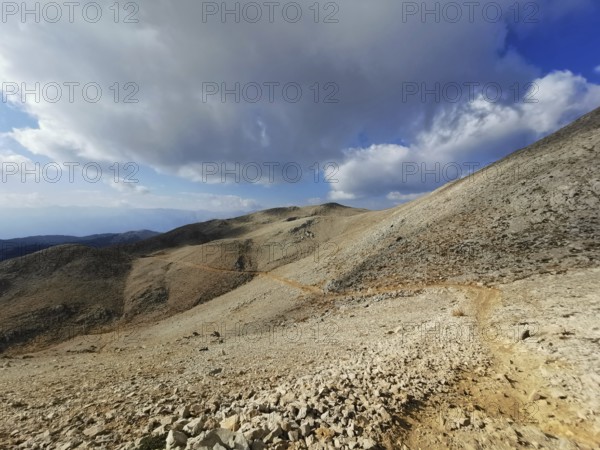 Open mountain trail on Tahtali Dagi under a partly cloudy sky with a wide view, climbing Tahtali Dagi, Lycia, Turkey