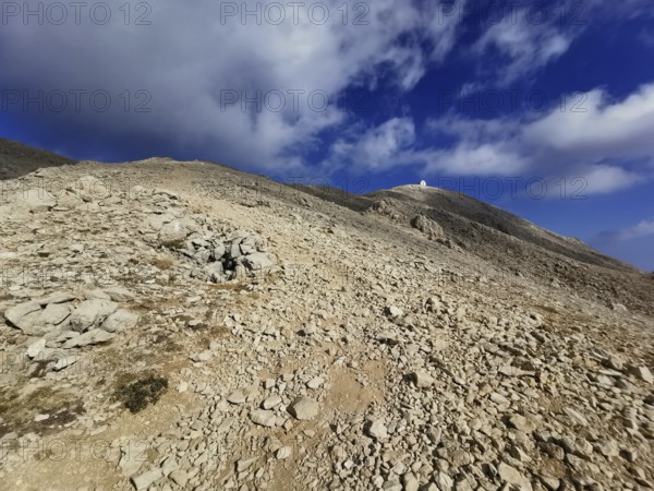 Rocky path leads to the summit of Tahtali Dagi under a partly cloudy sky, climbing Tahtali Dagi, Lycia, Turkey