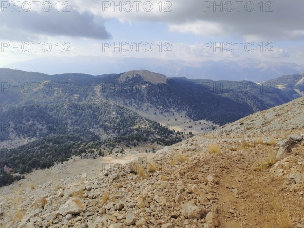 Extensive mountain view with wooded slopes and a rocky trail climb of Tahtali Dagi, Lycia, Turkey