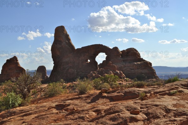 Turret Arch, a characteristic rock formation with an arch, surrounded by desert landscape and light cloudy skies, Arches National Park, Utah, USA