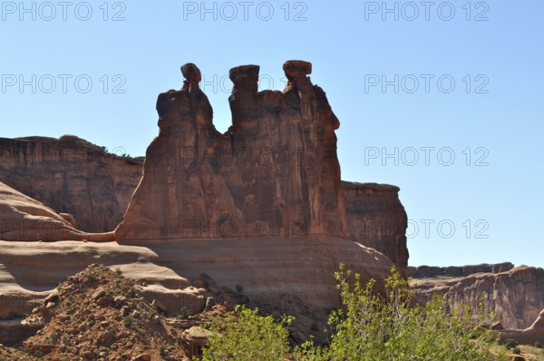 Three Gossips, a majestic red sandstone rock formation rising above a bright blue sky, Arches National Park, Utah, USA