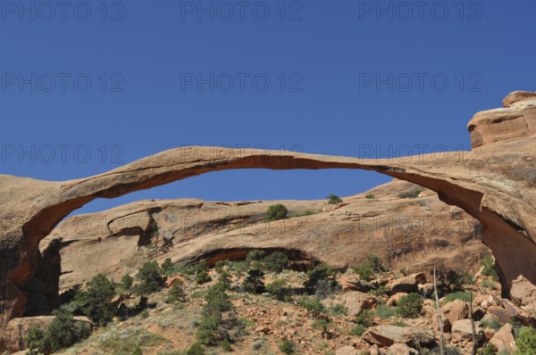 Landscape Arch, an impressive natural stone bridge against bright blue sky, Arches National Park, Utah, USA