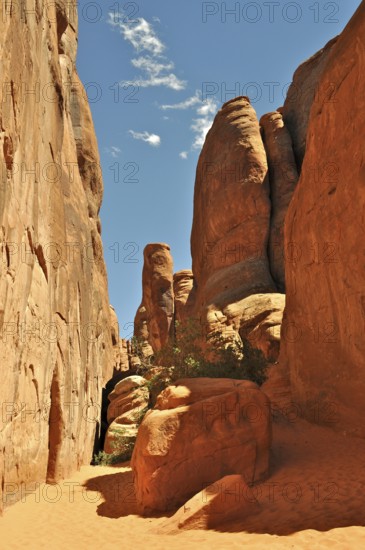 Narrow gorge surrounded by high rock walls with intense sunlight, Arches National Park, Utah, USA