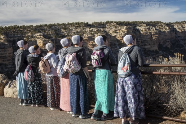 Grand Canyon National Park, Arizona. Young Mennonite women from Wisconsin, wearing traditional prayer coverings and ankle-length dresses, line up on the South Rim to view the Canyon