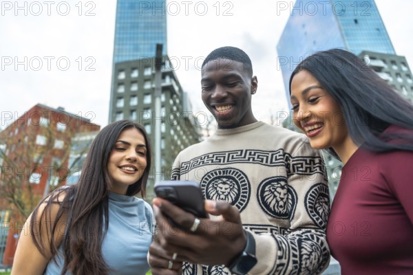 Group of diverse young adults laughing while looking at a mobile phone screen together, sharing a social media moment in an urban environment with modern buildings
