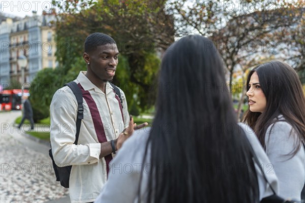Young multiracial friends animatedly discussing ideas and stories on a city street, sharing laughter, gestures and attentive listening during an informal urban campus meetup