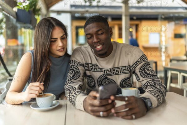Young diverse couple enjoying a moment together at a cafe, discussing content on a smartphone and drinking coffee, illustrating modern social interaction and digital connection