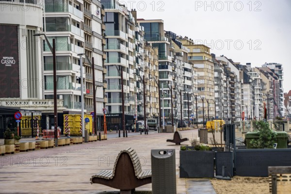 An urban promenade with modern high-rise buildings by the sea under cloudy sky, Zeedijk-Knokke, beach promenade in Knokke-Heist, on the North Sea beach, dreary winter day, mostly apartment buildings with rental or condominiums, high-rise buildings on the street, Belgium