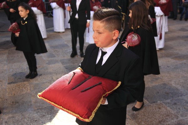 Sicily, Trapani, Good Friday mystery procession La Processione dei Misteri, groups accompany the procession with the mysteries, boy with a red pillow on the nails of the cross of Christ, symbolic
