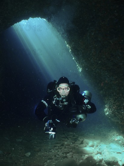 In an underwater cave, a diver moves through bright blue light. Fraskeric dive site, Stoja, Pula, Croatia, Mediterranean