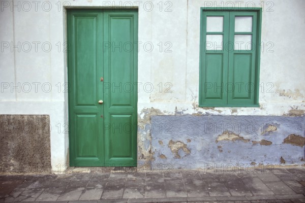 Landscape close-up of a green door and window in Arrecife, Lanzarote. Speckled plaster gives the bright façade an authentic, slightly aged character, Arrecife, Lanzarote