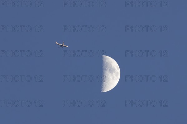 Airbus commercial passenger airliner jet aircraft of British airways in flight with the moon in the background, England, United Kingdom