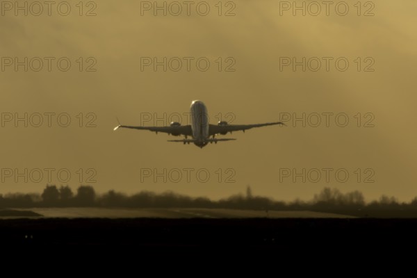 Airbus commercial passenger airliner jet aircraft taking off in flight silhouette at sunset at London Stansted airport, Essex, England, United Kingdom
