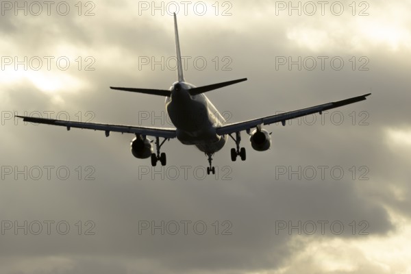 Commercial passenger airliner jet aircraft in flight on approach to land at sunset at London Stansted airport, Essex, England, United Kingdom