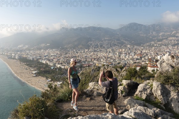 Alanya, Turkey. April 7th 2021 Tourists posing for photographs on the mountain overlooking the city of Alanya and Kleopatra beach on the Mediterranean coast of Turkey