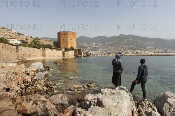 Alanya, Turkey. April 7th 2021 Turkish tourists enjoy the view of the ancient walls of Alanya castle and the Red Tower on the Mediterranean coast of Turkey