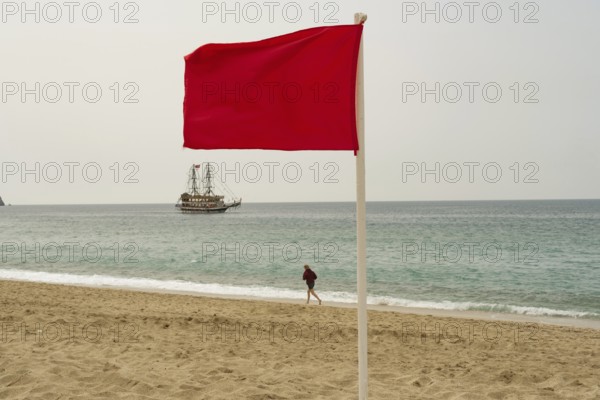 Alanya, Turkey. April 6th 2021 Red flag flying on an empty Turkish beach in the tourist resort city of Alanya, the Mediterranean coast of Turkey