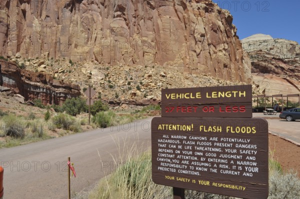 Information sign about possible flash flood hazards in a rocky canyon under clear skies, Capitol Reef National Park, Utha, USA