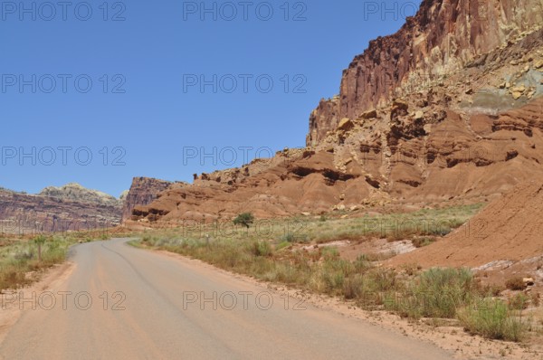 Deserted road through a wild red rock landscape under blue sky, Capitol Reef National Park, Utha, USA