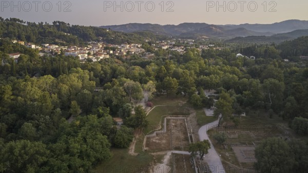 Soft morning light, village, ancient gymnasium, North-Eastern Propylon, Prytaneion, overview of an urban landscape surrounded by wooded areas and hills at dusk, drone shot, archaeological site, Ancient Olympia, Olympia, Peloponnese, Greece
