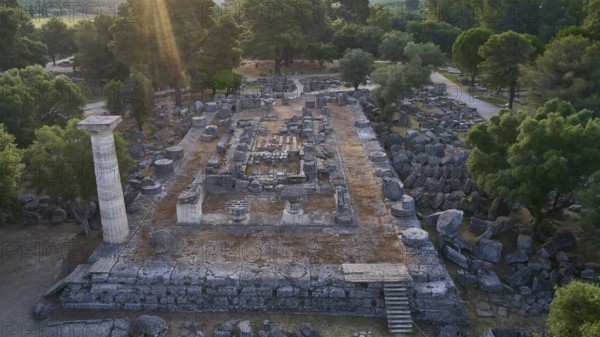 Temple of Zeus in backlight, ancient ruins surrounded by trees, with a stone column and archaeological structures, drone shot, archaeological site, Ancient Olympia, Olympia, Peloponnese, Greece