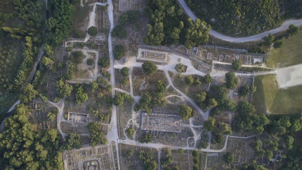 Olympic excavation site from high altitude, Temple of Zeus, Temple of Hera, Leonidaion, Palestra Philippeion, etc. Aerial view of an ancient site with ruins surrounded by lush vegetation and a network of trails, drone shot, archaeological site, Ancient Olympia, Olympia, Peloponnese, Greece