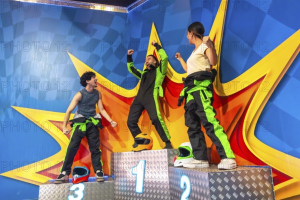 Joyful friends celebrating success on a racing podium, with the winner raising arms in triumph, expressing victory and happiness after a competitive karting event