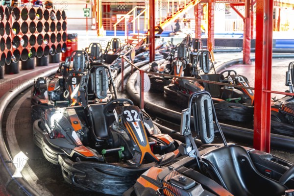 Go karts lining up on a designated track, preparing for a recreational racing session at an entertainment leisure facility, highlighting competition and speed