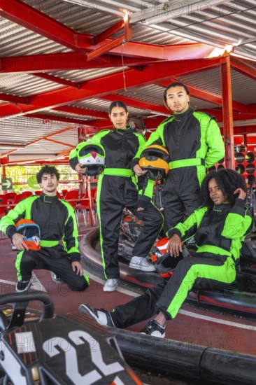Diverse group of young people wearing racing suits and holding helmets, preparing for a fun karting competition, embodying teamwork and leisure at an indoor track